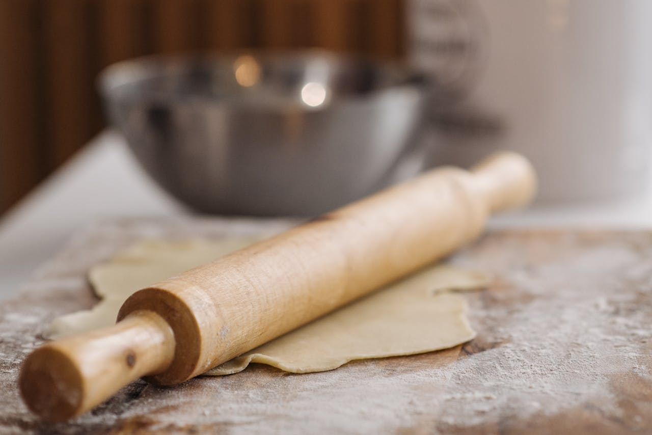 The Art of Drawing Readers In: Your attractive post title goes here Close-up of a wooden rolling pin resting on dough with flour and a bowl in the background.